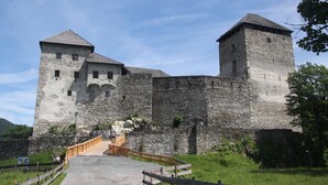 A historic stone castle with two prominent towers, a central entrance with a wooden bridge, and a surrounding stone wall. - 1 Studio Flat walking distance to ski lifts (we have 2 in the same building) (Kaprun)