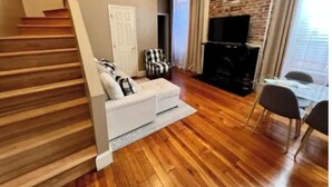 Uma sala de estar com um sofá branco, poltronas preto e branco, uma lareira e uma escada.