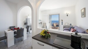 A modern kitchen with a dining area, a view of the sea, and a living area with a sofa and a coffee machine. - Villa Ecuba - Villa for groups in a strategic position (Praiano)