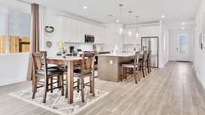 Una cocina moderna con armarios blancos, una isla central e iluminación colgante.