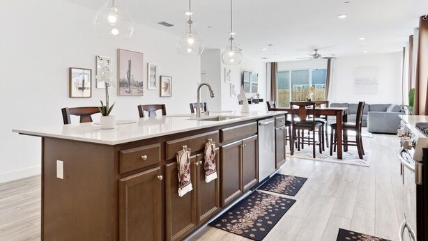 Una cocina moderna con una isla central, iluminación colgante y un área de comedor con vistas.