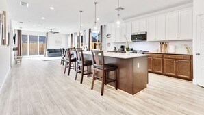 Una cocina moderna con armarios blancos, una isla central e iluminación colgante.