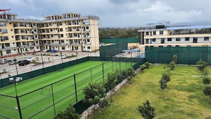 Un campo sportivo con manto erboso, circondato da una recinzione e adiacente a un edificio a più piani con balconi.