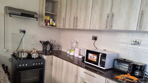 Una cucina con pensili e basi in legno, un fornello, un forno a microonde e un tostapane.