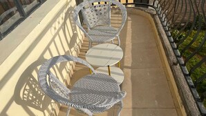 Un balcone con due sedie in vimini e un tavolino rotondo.