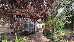Un patio con una mesa y sillas, rodeado de plantas y un pequeño jardín.