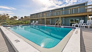 A rectangular pool with a wooden deck and lounge chairs. - Cozy Beach Escape -saltwater pool - Poolside Suite (Melbourne Beach)