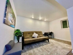 Relax in this serene space with a sofa, potted plant, and natural light pouring in through the window.