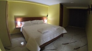 Habitación de hotel con cama, lámparas de noche y piso de baldosas.