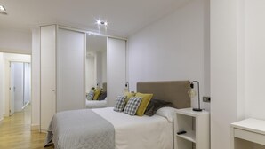 A modern bedroom with a large bed, bedside tables, a mirror, and a wardrobe. - Spacious and cosy in a central neighbourhood, Indautxu. (Bilbao)
