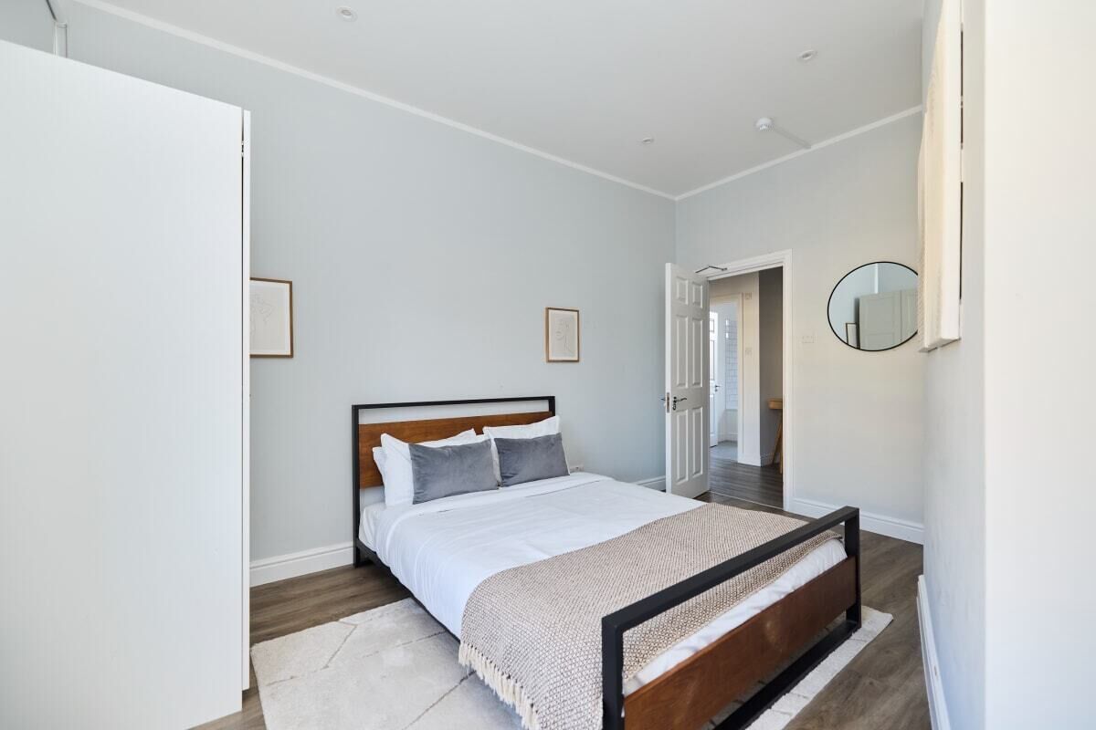 A bedroom with a bed, a bedside table, and a mirror on the wall.