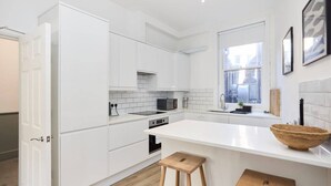 A modern kitchen with white cabinetry, a large island, and a window providing natural light.