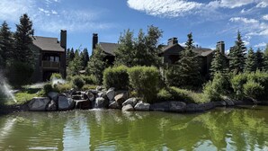 A lakeside view of a lodge with multiple buildings, a waterfall, and surrounding greenery. - Snowcreek Vi The Lodges #1167 4 Bedroom Condo by RedAwning (Mammoth Lakes)