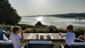 Two children sitting at a wooden table with a view of a lake.