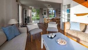 A spacious living room with a sofa, armchairs, a coffee table, and a dining area with a table and chairs.