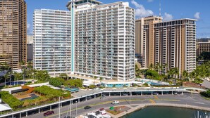 Un hotel de gran altura con varios pisos, un patio central y un puerto deportivo con barcos.