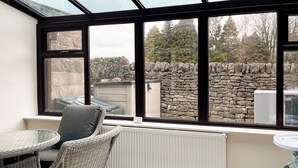 A sunroom with a view of a stone wall and trees. - 2 bedroom accommodation in Monyash (Monyash)