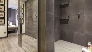 A modern bathroom with a walk-in shower, dark tiled walls, and a wooden floor. - Sophisticated Flat in Trendy Poble Sec (Barcelona)