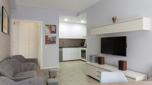 En moderne stue med en grå sofasæt, et træspisebord og et køkken i baggrunden.