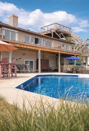 Une maison à deux étages dotée d’une piscine, de mobilier d’extérieur et d’un patio couvert.