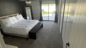 A bedroom with a bed, a bench, a ceiling fan, and a sliding door leading to a balcony. - Ended up in Havasu (Lake Havasu City)