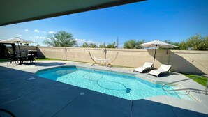 A swimming pool with lounge chairs and a table, surrounded by a low wall and trees. - Ended up in Havasu (Lake Havasu City)