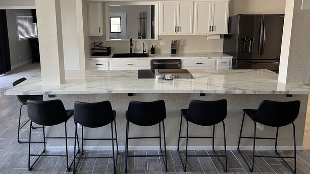 A modern kitchen with white cabinets, a large island with bar stools, and stainless steel appliances. - Ended up in Havasu (Lake Havasu City)