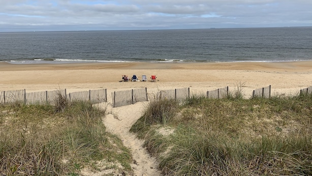 En strand med et træhegn og en sti til strandstole.