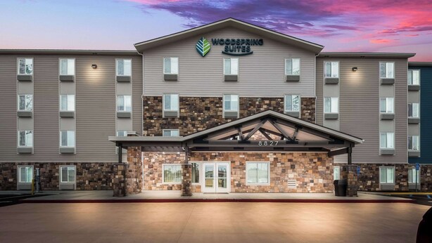 A hotel with a stone facade, multiple windows, and a sign reading "Woodspring Suites."