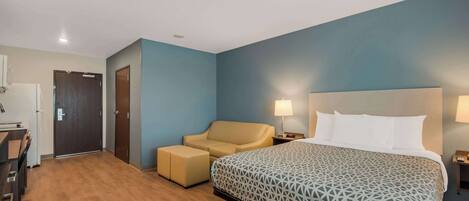 Una habitación de hotel con cama, sofá, escritorio y puerta.