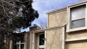 A two-story house with a garage, a front porch, and a small front yard with a tree and a brick border. - Spacious home with Tranquil backyard (Aurora)