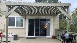 A covered deck with a pergola, a sliding glass door, a barbecue grill, and outdoor furniture. - Spacious home with Tranquil backyard (Aurora)
