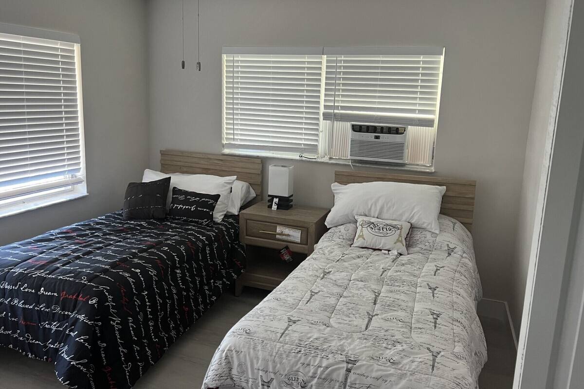 Une chambre avec deux lits, un ventilateur de plafond et un appareil de climatisation.