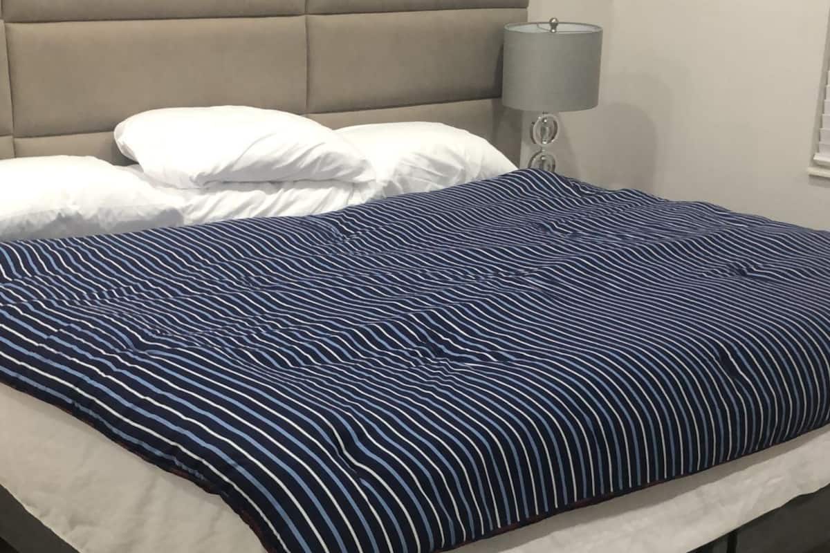 Un lit avec une couverture à rayures, une tête de lit et une lampe de chevet.