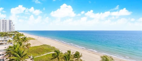 På stranden, hvidt sand, liggestole, parasoller