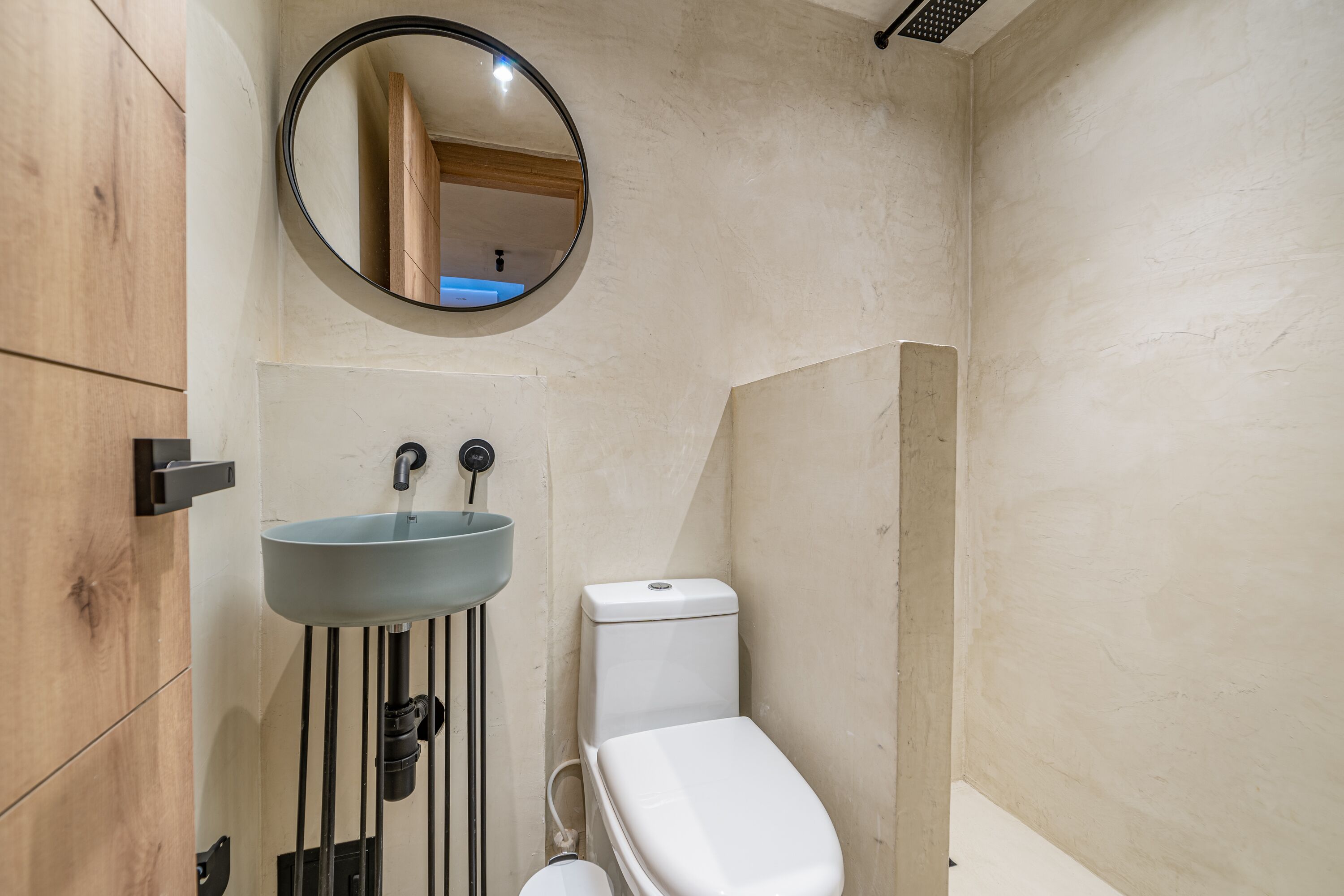 A bathroom with a round mirror, a sink, and a toilet.