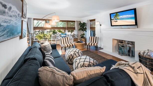 Ett vardagsrum med en soffa, fåtöljer, en tv och en öppen spis.