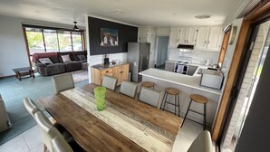 Une cuisine moderne avec des meubles blancs, une table à manger en bois et des tabourets de bar.