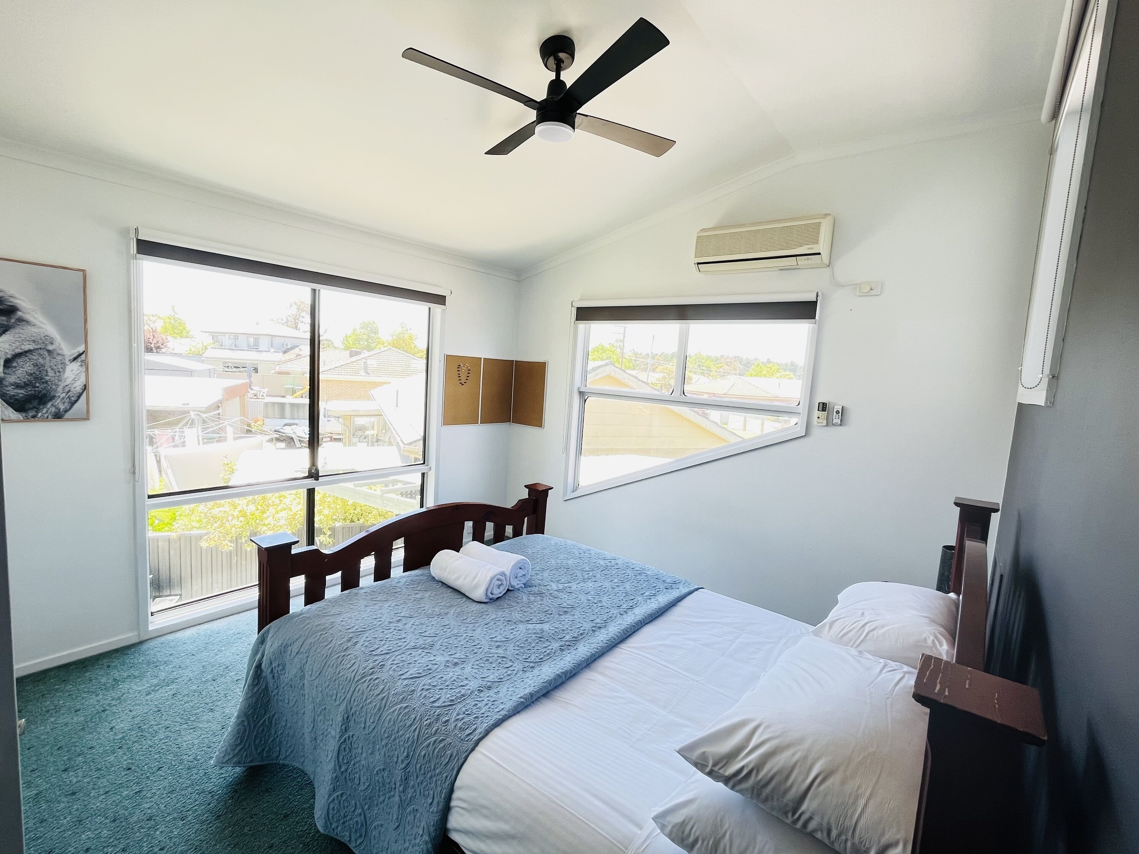 A bedroom with a bed, a ceiling fan, a window, and an air conditioning unit.