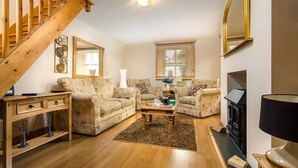 Una sala de estar con escalera, dos sofás, una mesa de centro y chimenea.