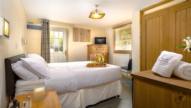 Una habitación de hotel con una cama, un aparador de madera, un televisor y una ventana con persianas.