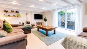 A modern living room with a sofa, a coffee table, and a TV mounted on the wall. - The Old Bakehouse - Within the Helland Barton Farm Collection (Delabole)
