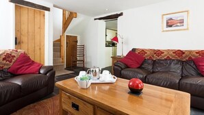 A living room with two leather sofas, a wooden coffee table with a teapot and cups, and a red decorative item.