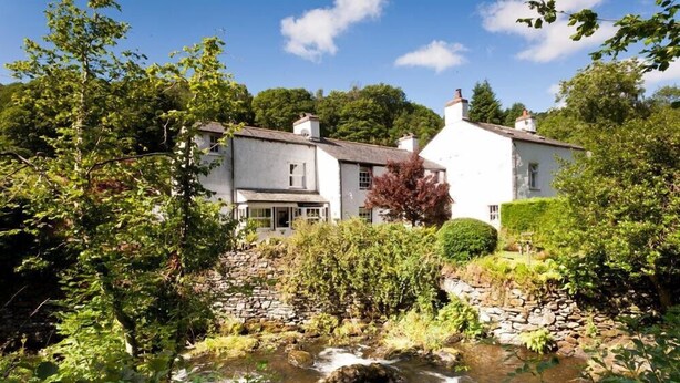 A white building with a stone pathway leading to a stream.