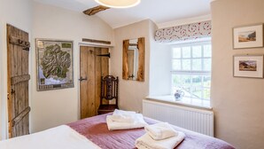 Ein Schlafzimmer mit einem Bett, einer Holztür, einer Karte, einem Spiegel, einem Fenster mit Blick und einem Heizkörper.