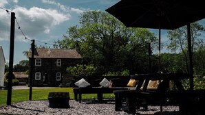 An outdoor seating area with a bench, a table, and a large umbrella. - Newby Bridge House (Ulverston)