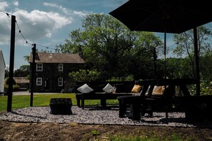 An outdoor seating area with a bench, a table, and a large umbrella. - Newby Bridge House (Ulverston)