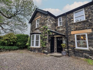 A stone building with a corner entrance, a small porch, and a gravel driveway. - Newby Bridge House (Ulverston)