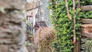 A rustic stone building with a wooden fence and a birdhouse. - Hideaway Cottage (Ambleside)