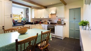 Una cocina con armarios blancos, una mesa de comedor de madera y una pared decorativa de piedra.